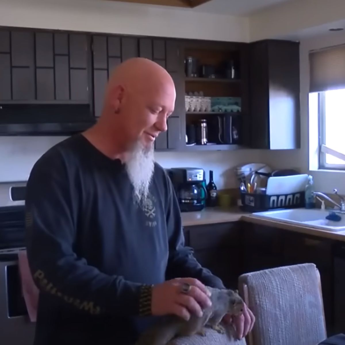 a man cuddles with a pet squirrel