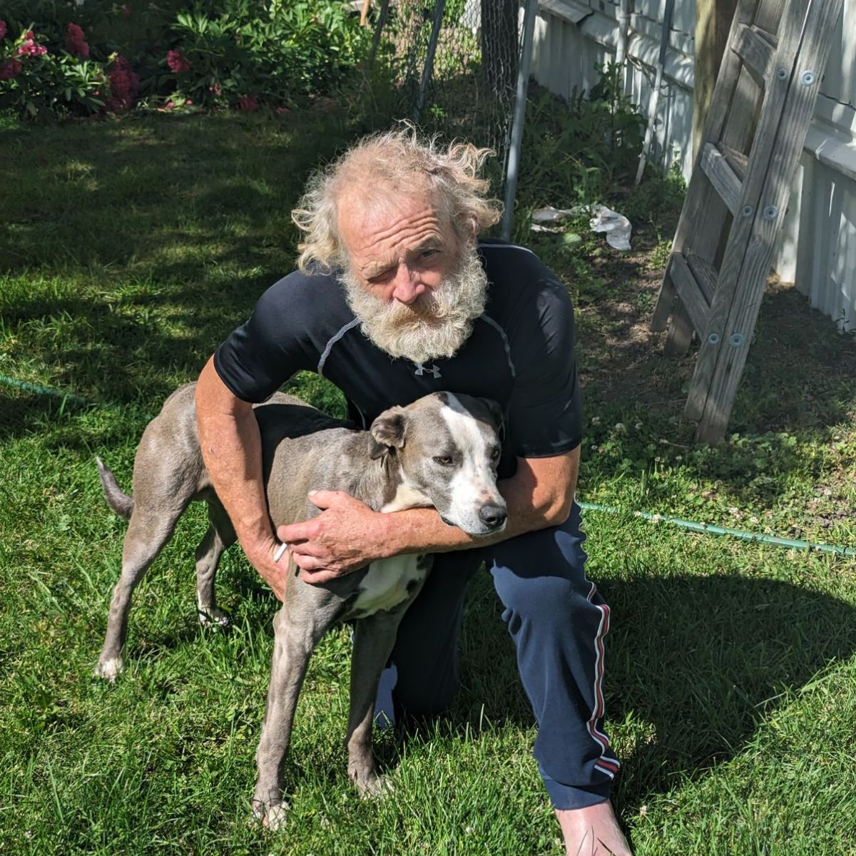 a senior man hugging dog