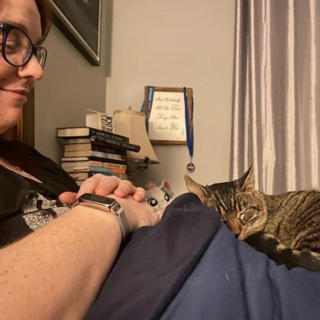 the woman enjoys looking at the cat while she sleeps