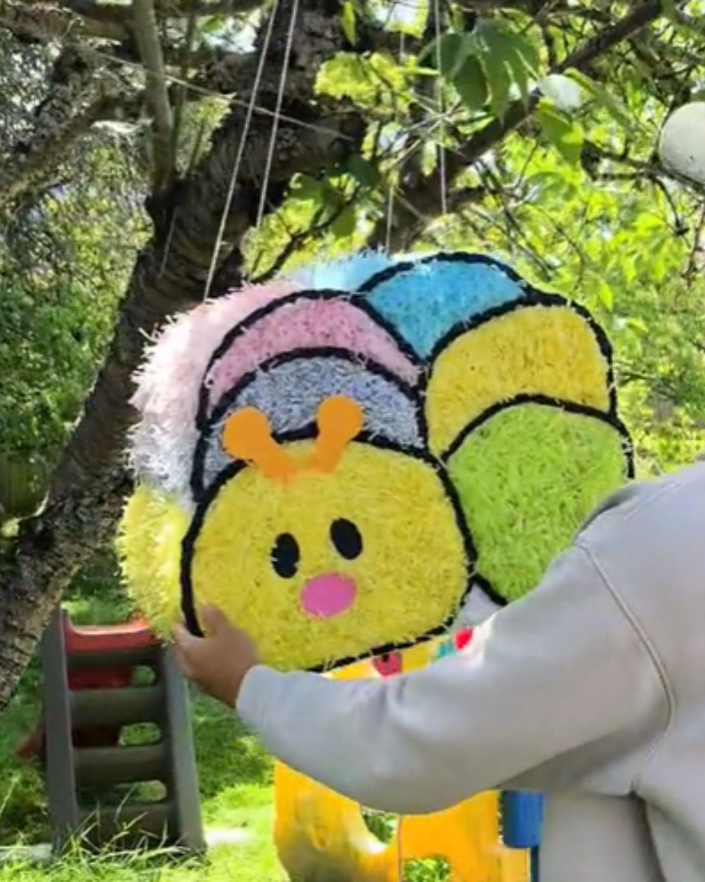 woman holding pinata tied to a tree