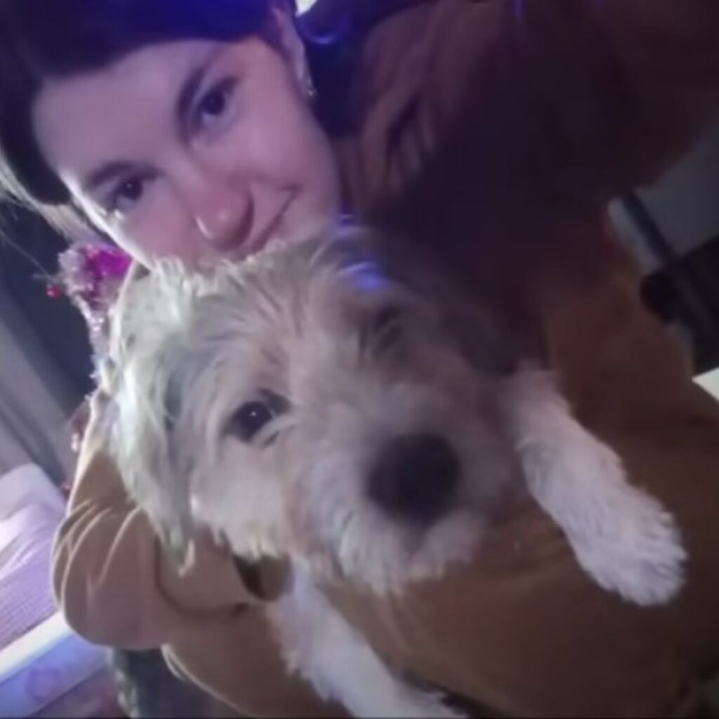 a girl takes a picture with a shaggy white dog