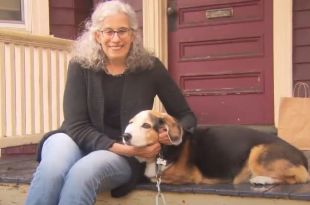 a woman is sitting in front of the door with a dog