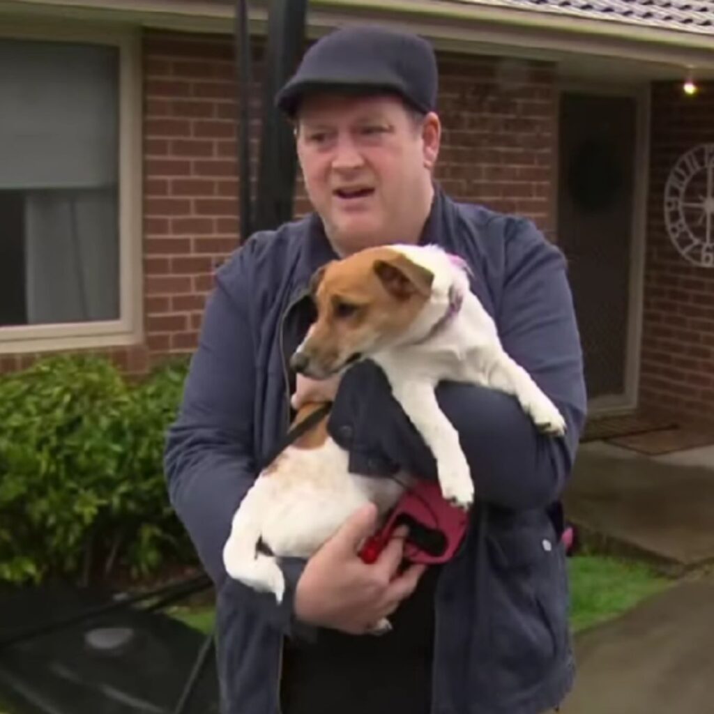 a man holds a Jack Russell in his arms