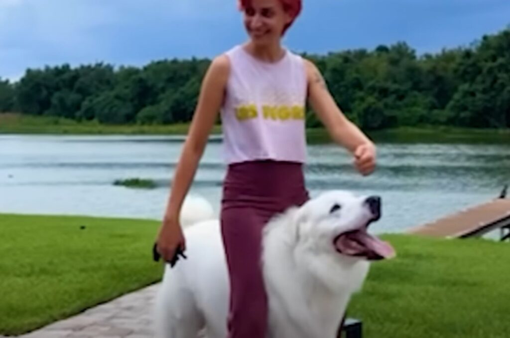 a smiling girl mounted a white dog