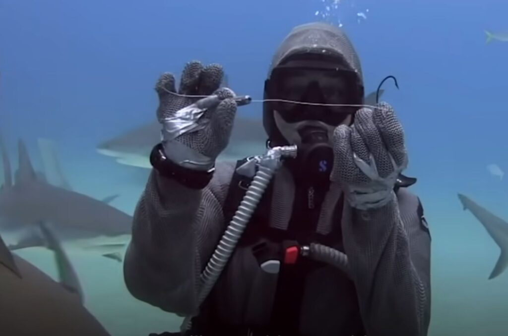 a woman underwater holds a needle in her hands