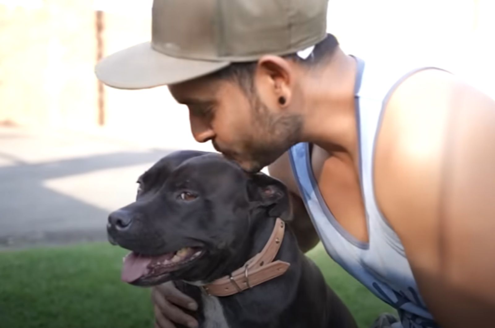 man kissing a black dog