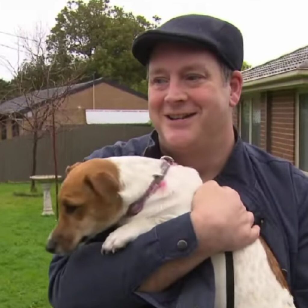 smiling man with a dog in his arms