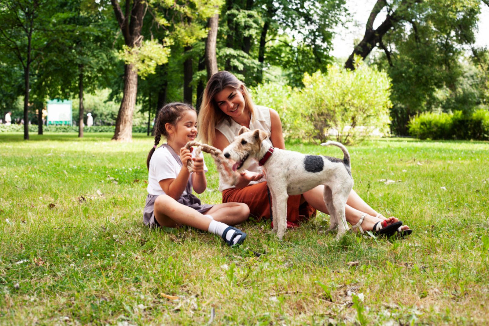 little girl and woman playing with dog