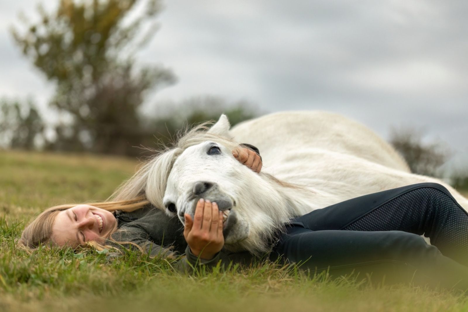 smiling woman lying with horse